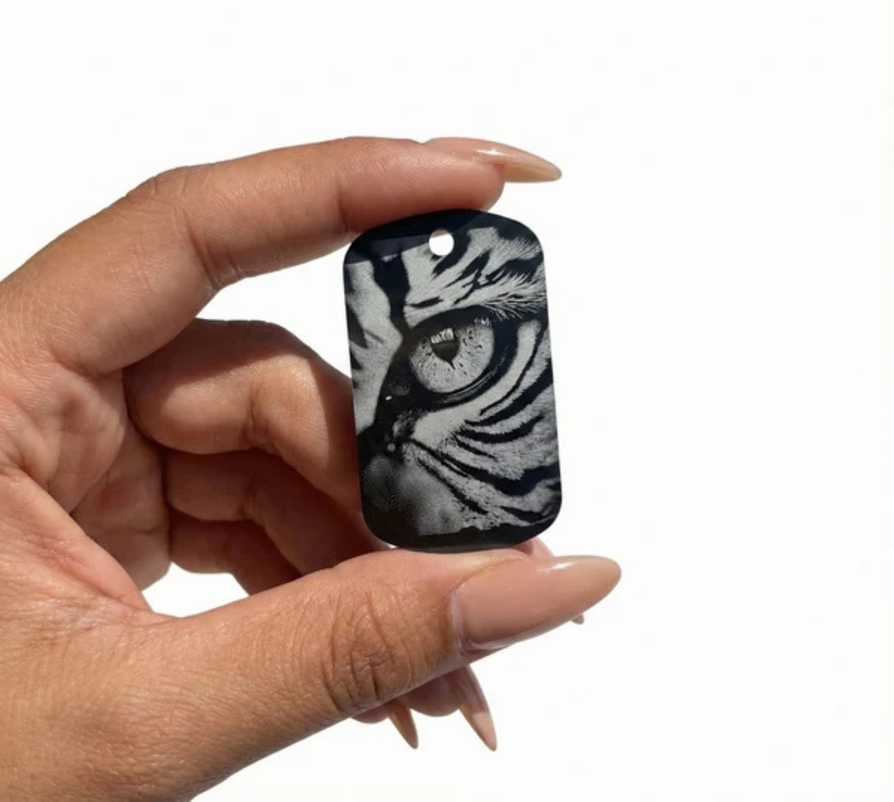 Custom engraved keychain with a tiger eye design, held in a hand